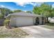 Charming single-story home featuring a two-car garage, arched entryway, and mature landscaping under a sunny sky at 5263 Kirkwood Ave, Spring Hill, FL 34608
