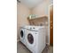 Bright laundry room with modern washing machines, storage shelf and wood door at 5263 Kirkwood Ave, Spring Hill, FL 34608