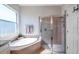 Bright bathroom featuring a soaking tub under a window and a glass-enclosed shower with tiled walls at 5518 72Nd E Ter, Ellenton, FL 34222