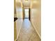 Well-lit hallway with tiled flooring leading towards a bright, sunlit entrance at 6446 Louisiana Ave, New Port Richey, FL 34653