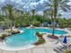 Grand Hampton community pool featuring a lagoon style pool, lounge chairs, and lush landscaping at 7927 Hampton Lake Dr, Tampa, FL 33647