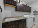 Well-equipped laundry room featuring a sink, granite countertops, dark wood cabinets, and modern washer/dryer at 7927 Hampton Lake Dr, Tampa, FL 33647