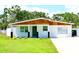 Charming single-story home with a well-maintained lawn, white paint, and a wood-accented roof and green front door at 8817 Audrey Ln, Tampa, FL 33615