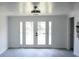 Bright, spacious living room featuring modern flooring and white French doors leading to the outdoors at 8817 Audrey Ln, Tampa, FL 33615