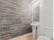 Modern powder room showcases a unique wood accent wall, pedestal sink, and contemporary lighting for a stylish touch at 10525 Lucaya Dr, Tampa, FL 33647