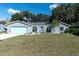 Charming single-story home with a well-manicured lawn, blue trim, and an attached garage at 10907 Kewanee Dr, Temple Terrace, FL 33617