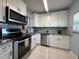 Bright kitchen features white cabinetry, granite countertops, stainless steel appliances and tile flooring at 11485 Oakhurst Rd # 319, Largo, FL 33774