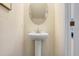 Clean half bath featuring a pedestal sink with oval mirror and neutral color scheme at 11718 Blackbrook Ct, Seffner, FL 33584