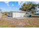Bright, white home featuring an entrance door, a small patio, and low-maintenance landscaping under a blue, cloudy sky at 1499 Janet Pl, Englewood, FL 34223
