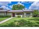 Charming single-story villa with a well-manicured lawn, sidewalk and mature trees at 150 James Ct, Oldsmar, FL 34677