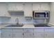 Well-maintained kitchen featuring white cabinets, granite counters, and modern sink at 200 Glennes Ln # 205, Dunedin, FL 34698