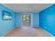 Bright living room with blue walls, light carpet, and a sliding door to the patio at 200 Glennes Ln # 205, Dunedin, FL 34698
