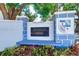 Entrance signage for a 55+ community, featuring stone pillars and colorful landscaping at 200 Glennes Ln # 205, Dunedin, FL 34698