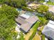 An aerial view of a home showcasing a backyard pool, solar panels, lush landscaping, and the surrounding neighborhood at 2671 Clubhouse N Dr, Clearwater, FL 33761