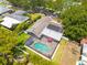 Aerial view featuring a home with a screened-in pool, solar panels, surrounded by lush greenery in a residential area at 2671 Clubhouse N Dr, Clearwater, FL 33761