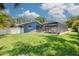 Spacious backyard with a screened-in pool, lush green lawn, white privacy fence, and the home's exterior at 2671 Clubhouse N Dr, Clearwater, FL 33761