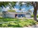 Charming home with a well-manicured lawn, mature trees, and a welcoming red front door at 2671 Clubhouse N Dr, Clearwater, FL 33761