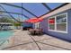 Outdoor patio with a brick-paved deck, dining set under a red umbrella, and a view of the sparkling swimming pool at 2671 Clubhouse N Dr, Clearwater, FL 33761