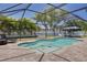 Inviting screened-in pool area with turtle design, brick pavers, an umbrella-covered seating area, and manicured landscaping at 2671 Clubhouse N Dr, Clearwater, FL 33761