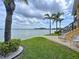 Beautiful backyard featuring a waterfront view, green lawn, palm trees, and a charming patio area at 2675 St Josephs E Dr # C, Dunedin, FL 34698