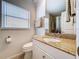 Bathroom with granite countertop, white cabinets, toilet, and window at 2675 St Josephs E Dr # C, Dunedin, FL 34698