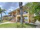 Inviting two-story condo with black railing, a combination of grass, palm trees, and a patio area at 2675 St Josephs E Dr # C, Dunedin, FL 34698
