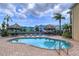 Community kidney-shaped pool features brick pavers, loungers, Tiki huts, and waterfront views at 2675 St Josephs E Dr # C, Dunedin, FL 34698