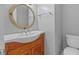 Cozy bathroom featuring a wooden vanity with a white sink and a round mirror above the toilet at 305 Bryan Oak Ave, Brandon, FL 33511