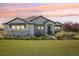 Charming single-story home with stone accents, lush landscaping, and a neatly manicured front lawn at sunset at 32860 Drake Estates Way, Dade City, FL 33525