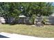 Fenced backyard features an interesting small rockery with palm trees and mature shade trees at 3414 Berry Blossom Ln, Plant City, FL 33567