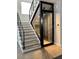Modern staircase features wood stairs, black metal railings, and a unique glass-encased wine cellar at 3420 Channelside Ct, Safety Harbor, FL 34695