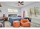 Bright bedroom with a ceiling fan, a bed with blue bedding, and a cozy seating area with two leather ottomans at 349 Belleair Ne Dr, St Petersburg, FL 33704