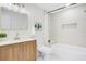 Bright bathroom featuring wood vanity, gold hardware, and shower over tub with white tile surround at 3512 Haines N Rd, St Petersburg, FL 33704