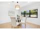Dining room featuring a glass table, upholstered chairs, and a modern light fixture beneath a bright window at 3512 Haines N Rd, St Petersburg, FL 33704