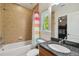 Bathroom featuring a tub with shower, granite vanity, and colorful striped shower curtain near the window at 3710 W San Pedro St, Tampa, FL 33629