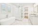 Bright bathroom featuring a soaking tub, glass-enclosed shower, and marble countertops and flooring at 3821 W Vasconia St, Tampa, FL 33629