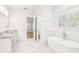 Bright bathroom with a soaking tub, double vanity with marble countertops, and natural light from shuttered windows at 3821 W Vasconia St, Tampa, FL 33629