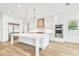 A bright kitchen boasts white cabinets, stainless steel appliances, and a large island with quartz countertops at 3821 W Vasconia St, Tampa, FL 33629