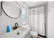 Modern bathroom featuring a stylish black faucet, round mirror, and walk-in shower with white curtain at 4013 W Waterman Ave, Tampa, FL 33609