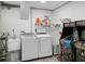 Functional laundry room featuring a washer, dryer, wash sink, and whimsical arcade games at 4013 W Waterman Ave, Tampa, FL 33609