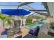 Relaxing screened-in pool area with a blue umbrella, outdoor furniture, and lush landscaping at 4013 W Waterman Ave, Tampa, FL 33609