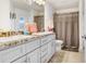 Well-lit bathroom with dual sinks, marble counters, neutral cabinets, and a shower/tub combo at 41043 Stanton Hall Dr, Dade City, FL 33525