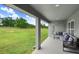 View of the covered patio with comfortable seating, overlooking the lush green backyard at 41043 Stanton Hall Dr, Dade City, FL 33525