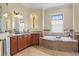 Bright bathroom featuring a soaking tub, dual sinks, wooden cabinets and granite counters at 601 Bosphorous Ave, Tampa, FL 33606