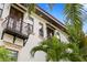 Exterior of a beautiful home showcasing a balcony, stucco walls, tile roof, and lush palm trees at 601 Bosphorous Ave, Tampa, FL 33606