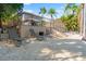 An outdoor lounge area with multiple lounge chairs on a gravel patio, enclosed by a fence and lush greenery at 6315 Marbella Blvd, Apollo Beach, FL 33572