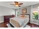 Cozy bedroom with hardwood floors, windows with palm tree views, ceiling fan and a dresser at 6315 Marbella Blvd, Apollo Beach, FL 33572