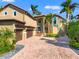 Elegant two-story home with a brick driveway, a two-car garage, and lush tropical landscaping at 6315 Marbella Blvd, Apollo Beach, FL 33572