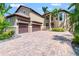 A luxurious home boasting a paver driveway, three-car garage, and lush tropical landscaping at 6315 Marbella Blvd, Apollo Beach, FL 33572