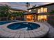 Night view of a backyard with a sparkling pool and spa, adjacent to a covered outdoor kitchen at 6315 Marbella Blvd, Apollo Beach, FL 33572